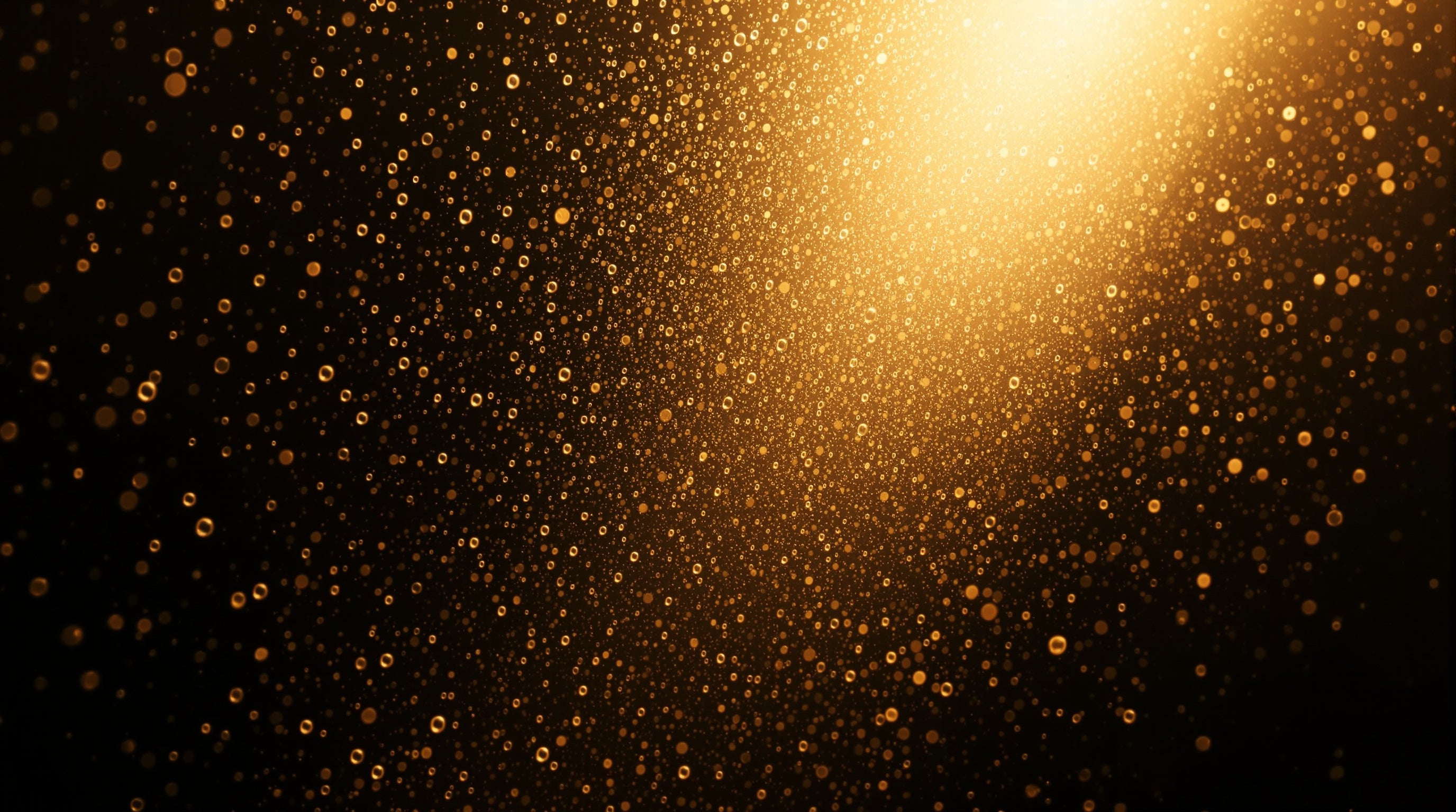 A fine suspended mist of golden droplets caught in a shaft of warm light against deep shadow