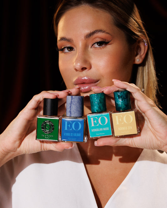 Model holding four Ensar Oud bottles under her lips, No 2 Tonkin, Kyara de Kalbar, Mongolian Musk and Borneo Zen, musky oud niche perfume decant