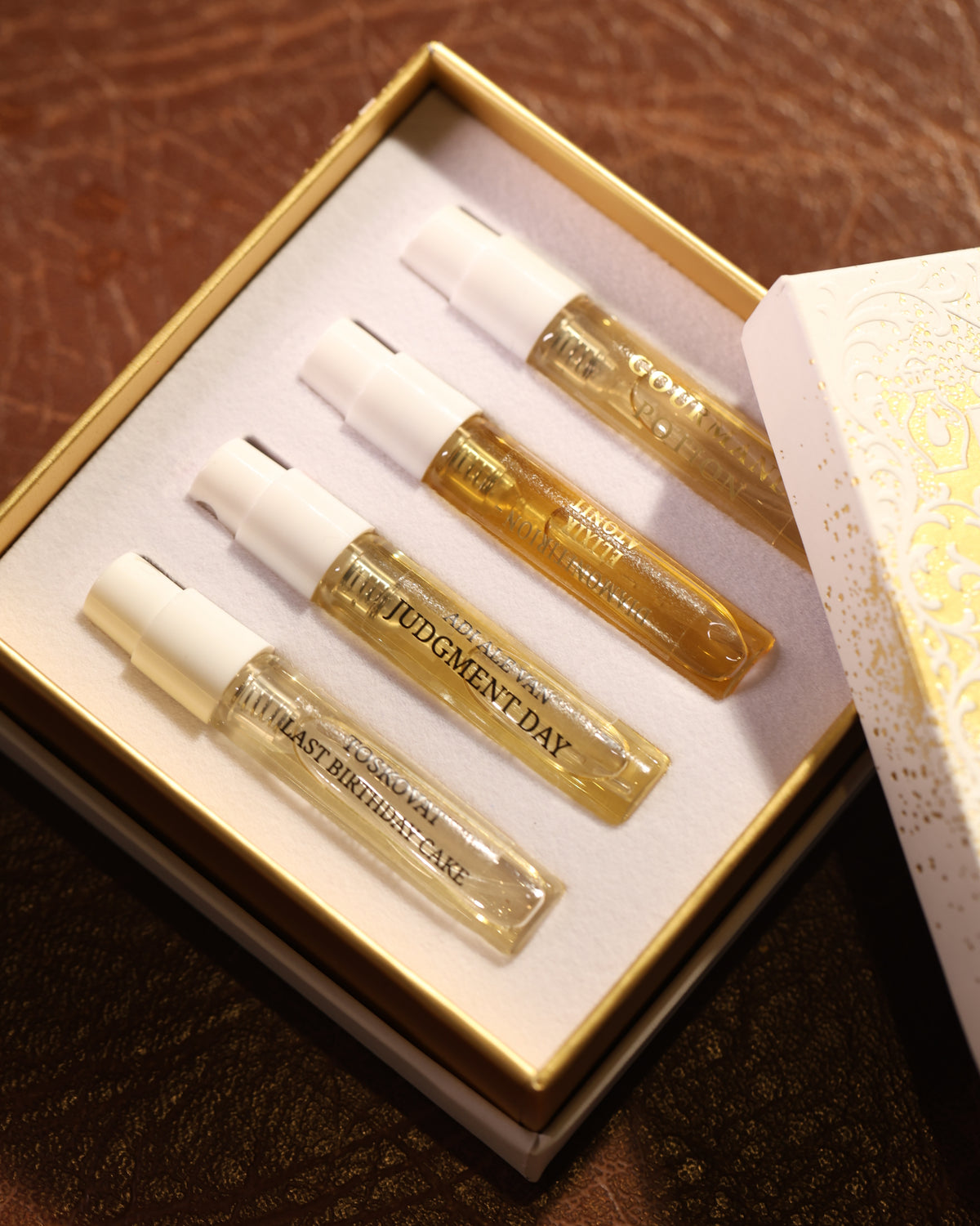 صينية ذهبية لمجموعة الاكتشاف من Gouttes Rares بسعة 4 x 2ml، تضم أربع بخاخات بسعة 2ml عليها ملصقات، معروضة كمثال: Toskovat Last Birthday Cake، Adi Ale Van Judgment Day، Diamonitirion Elixir Atonit و Gourmand Potion