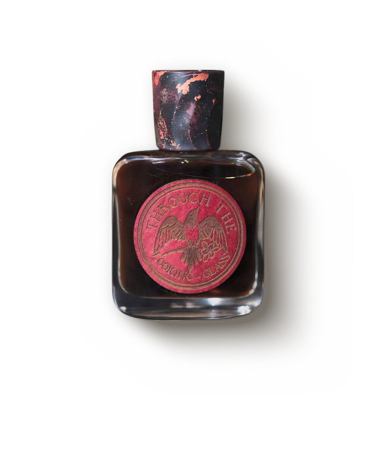Folkwinds Through the Looking Glass, front view: a dark square bottle under a marbled black and copper cap, its round red leather label showing a bird and Through the Looking Glass.