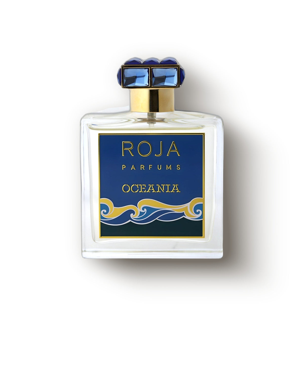 Botol Roja Oceania dengan tutup biru bertahtakan dan label ombak emas di latar abu-abu lembut, decant parfum niche akuatik