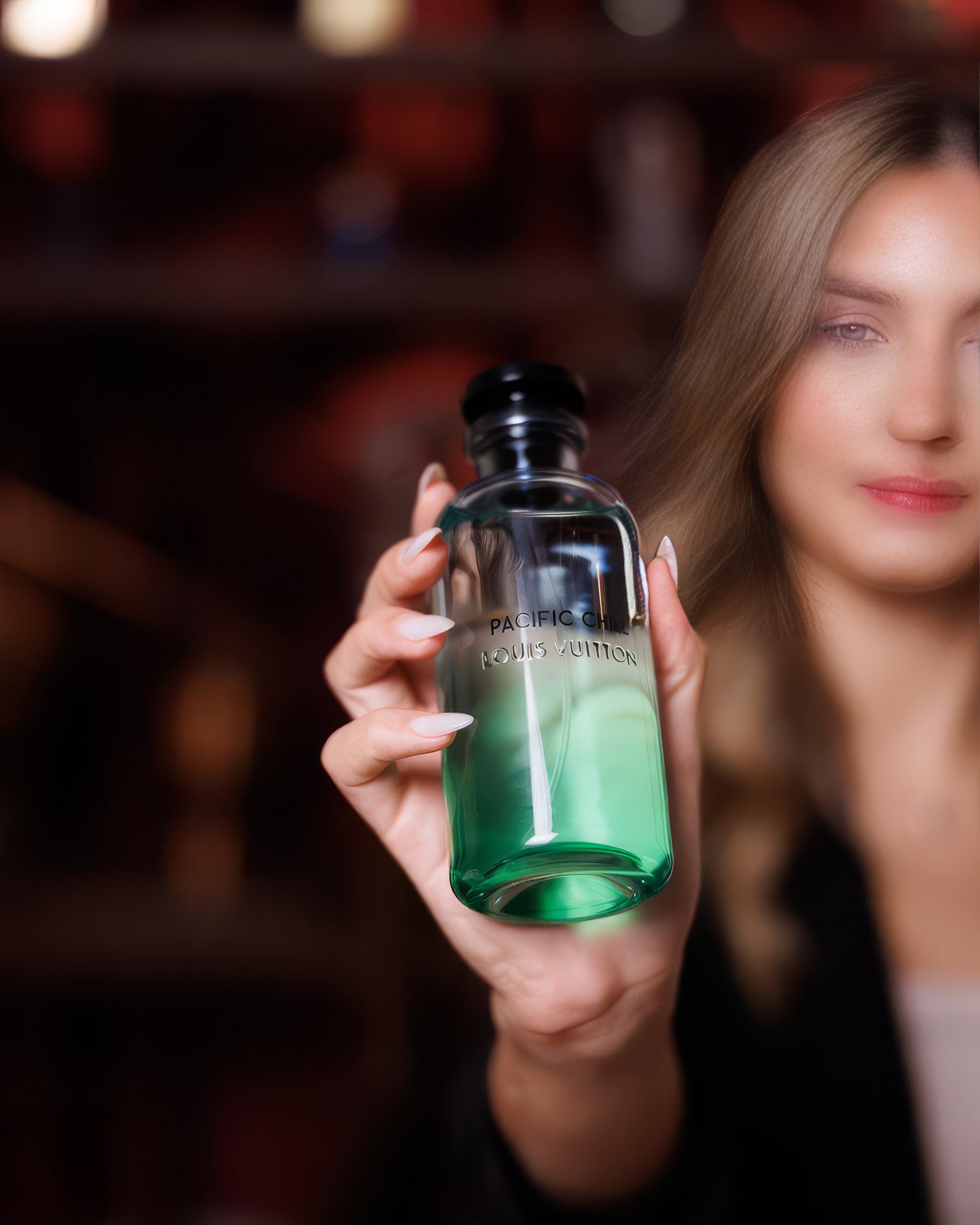 Blonde woman in a dark blazer holding the Louis Vuitton Pacific Chill flacon, aromatic citrus fragrance decant