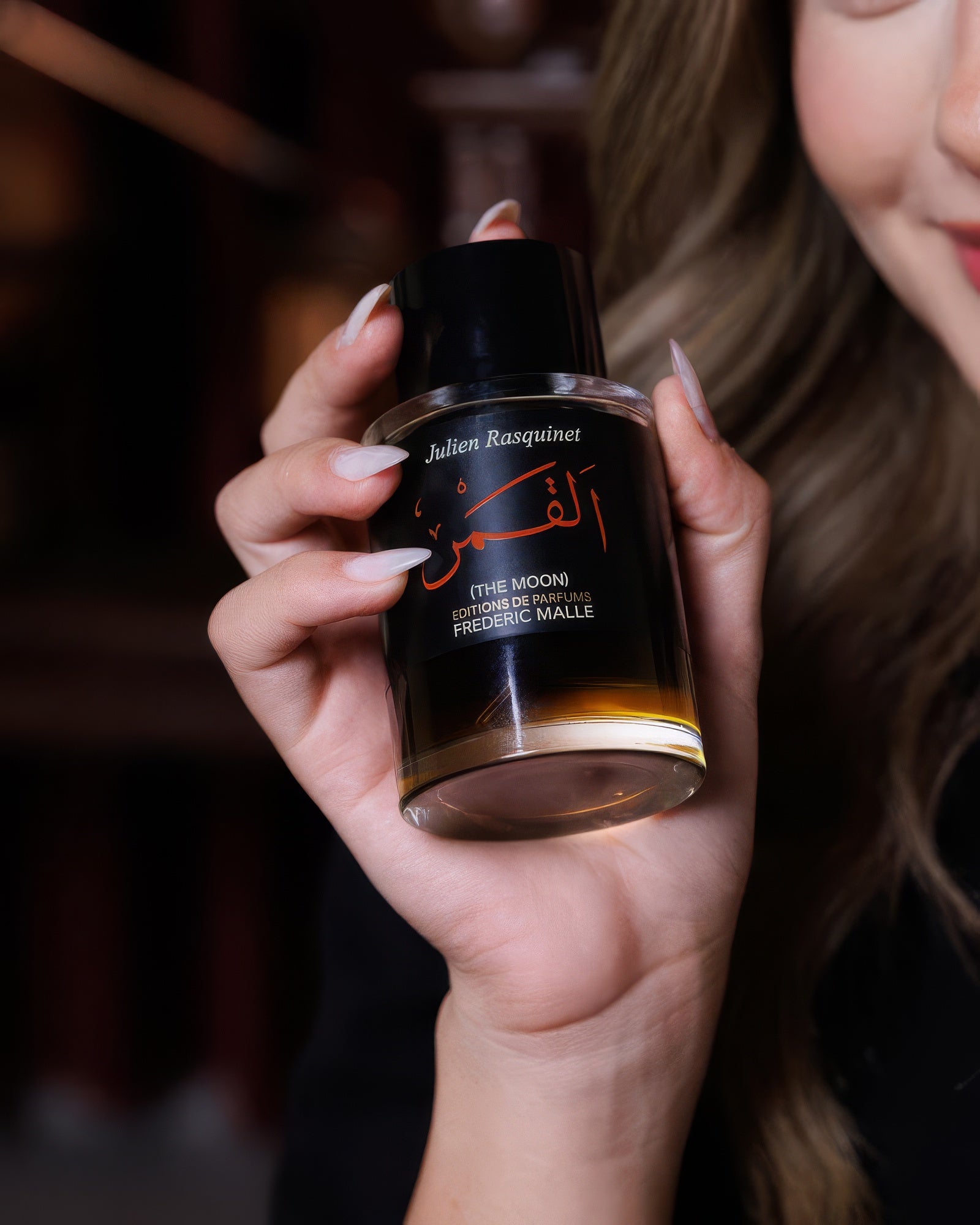 Frau hält den Frederic Malle The Moon Flakon neben ihr Gesicht, würzige Rose-Oud Nischenduft-Abfüllung