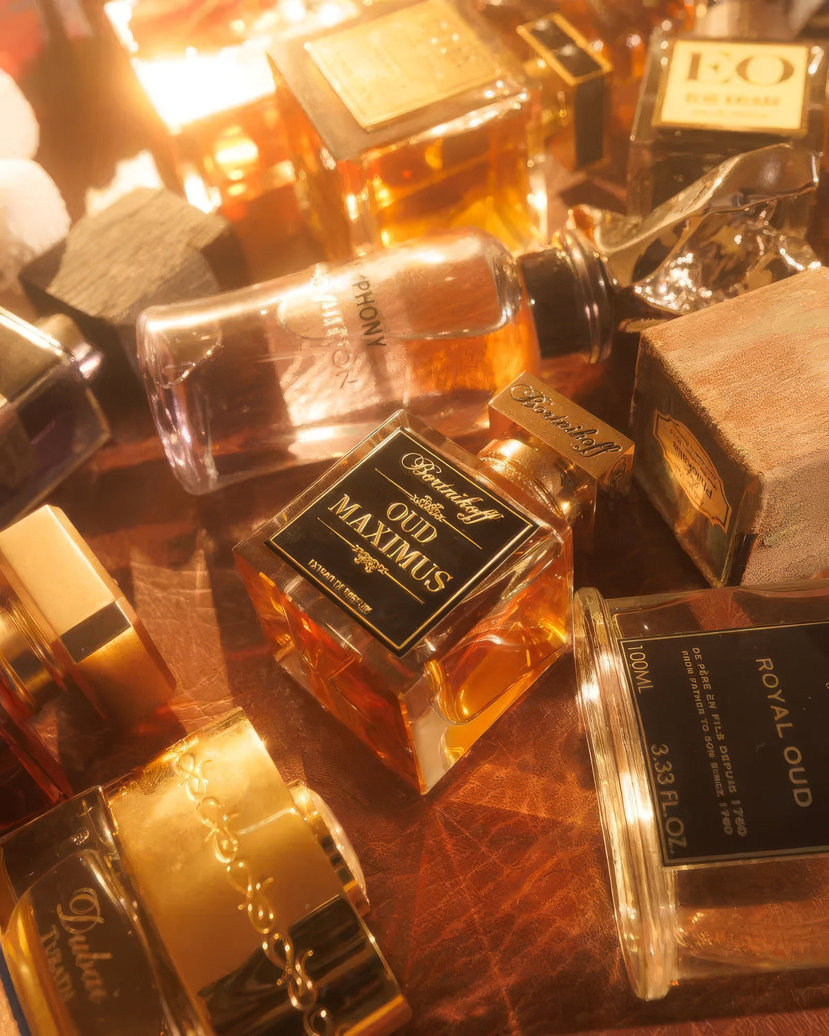 Bortnikoff Oud Maximus flacon amid glowing amber bottles on a leather table, rose and oud niche perfume decant