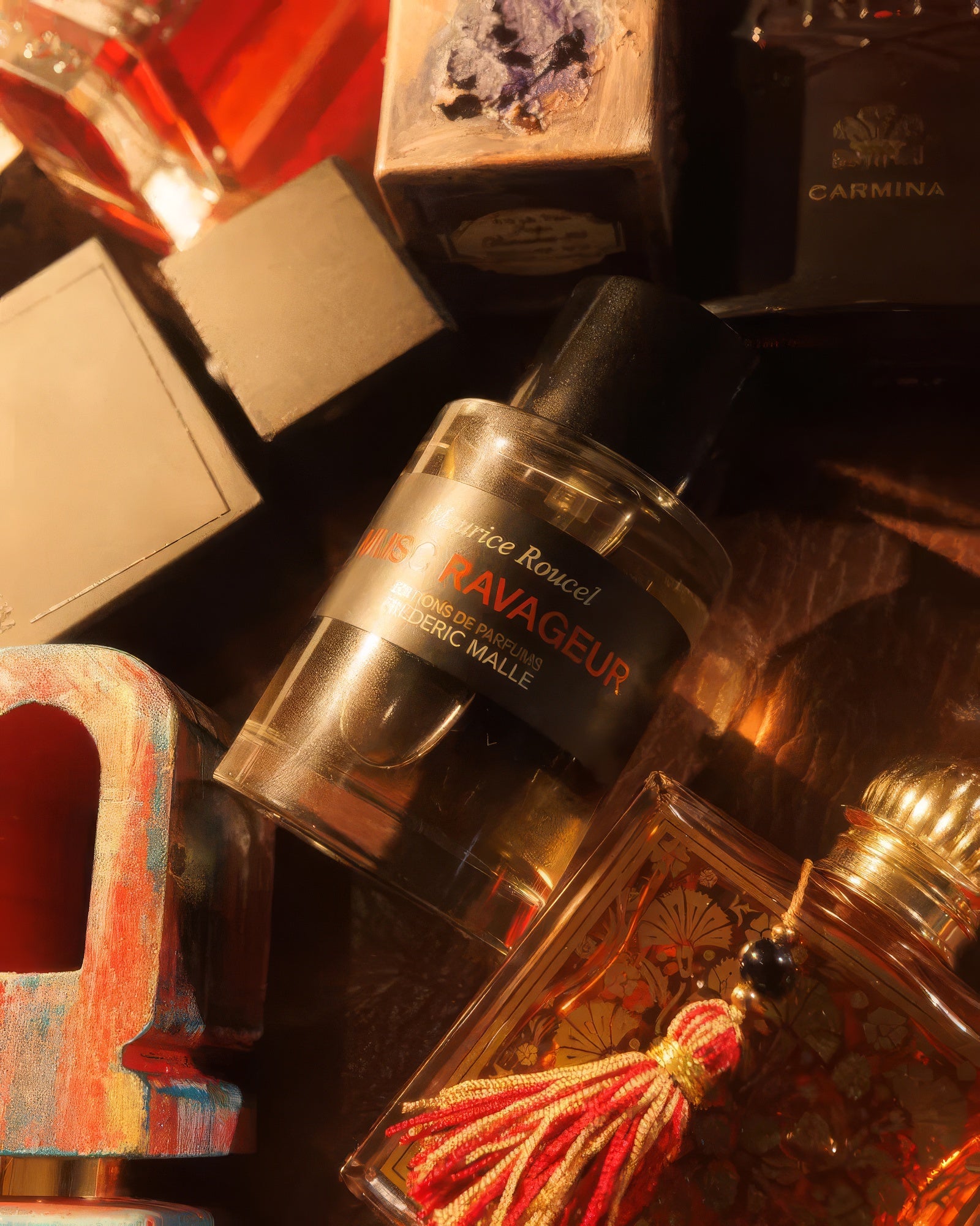 Frédéric Malle Musc Ravageur flacon nestled among bottles in warm golden light, musky niche fragrance decant