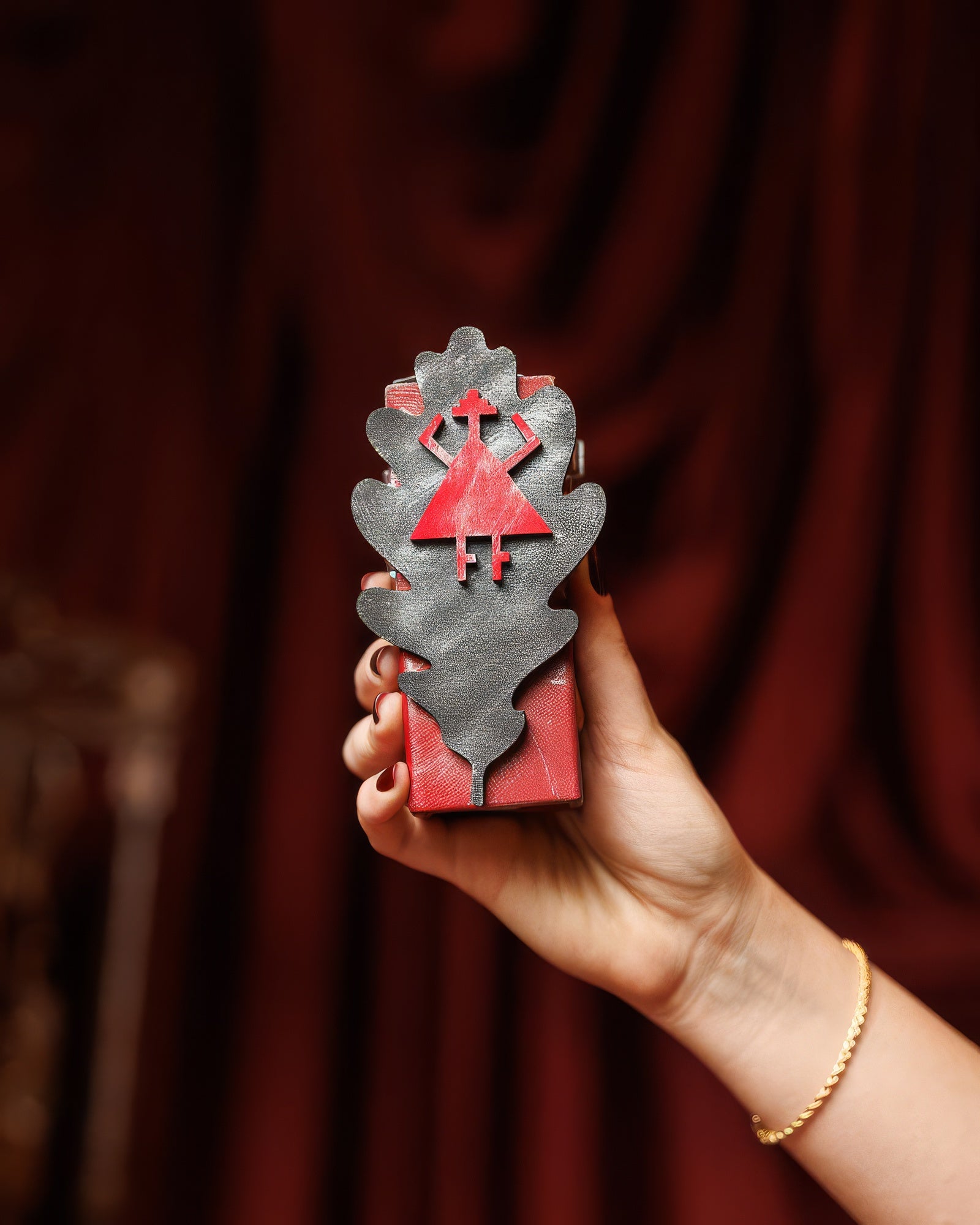 Hand holding the Adi Ale Van My Judgement Day flacon against red velvet, dark incense extrait de parfum sample