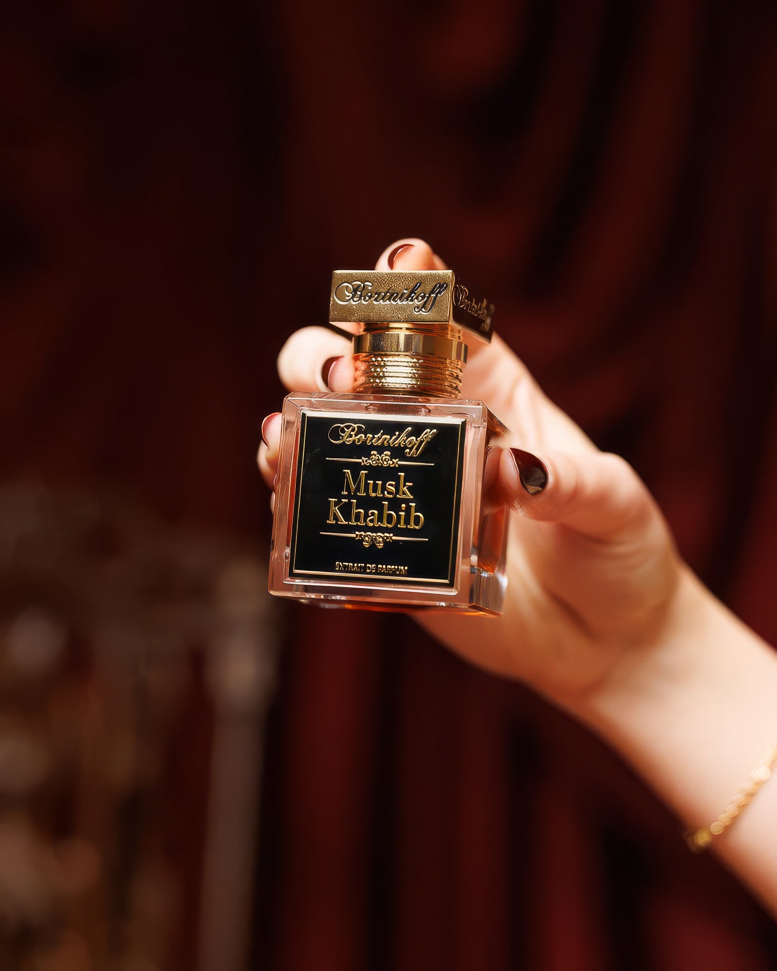 Hand holding the Bortnikoff Musk Khabib flacon against red velvet, ambery musk niche perfume decant
