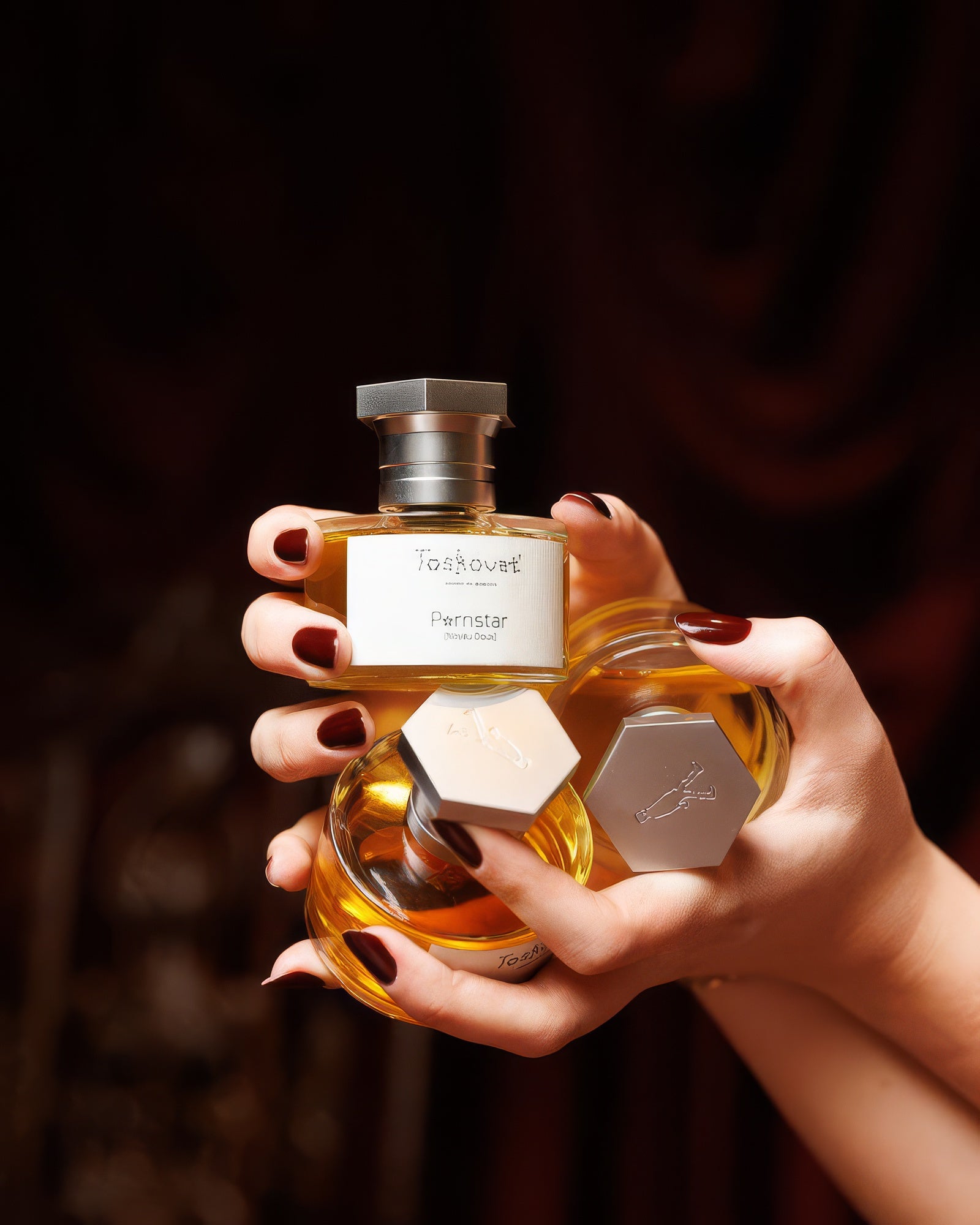 Mano curata che regge flaconi Toskovat Anarchist A♭ su sfondo scuro, campione di extrait de parfum legnoso e alcolico
