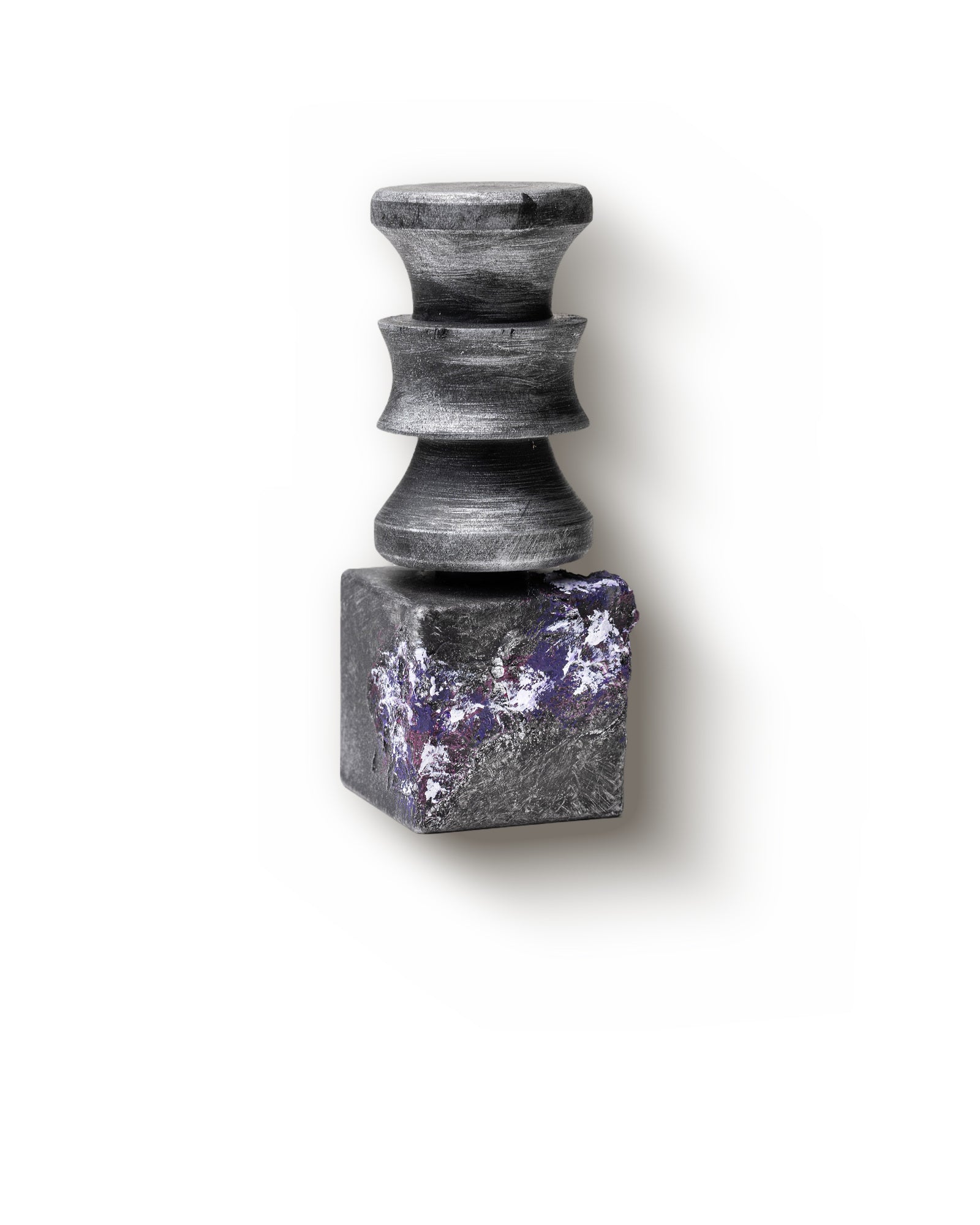 The same Labels of Feelings flacon turned three-quarters, the violet and white crust across the block catching the light, against a plain pale ground.