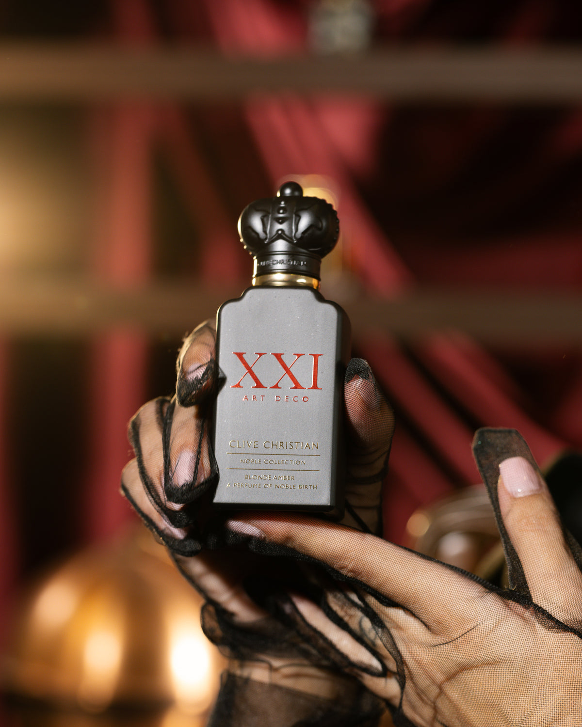 Clive Christian Blonde Amber slate grey flacon with red XXI Art Deco lettering, held in sheer black tulle gloves, ambery extrait de parfum decant