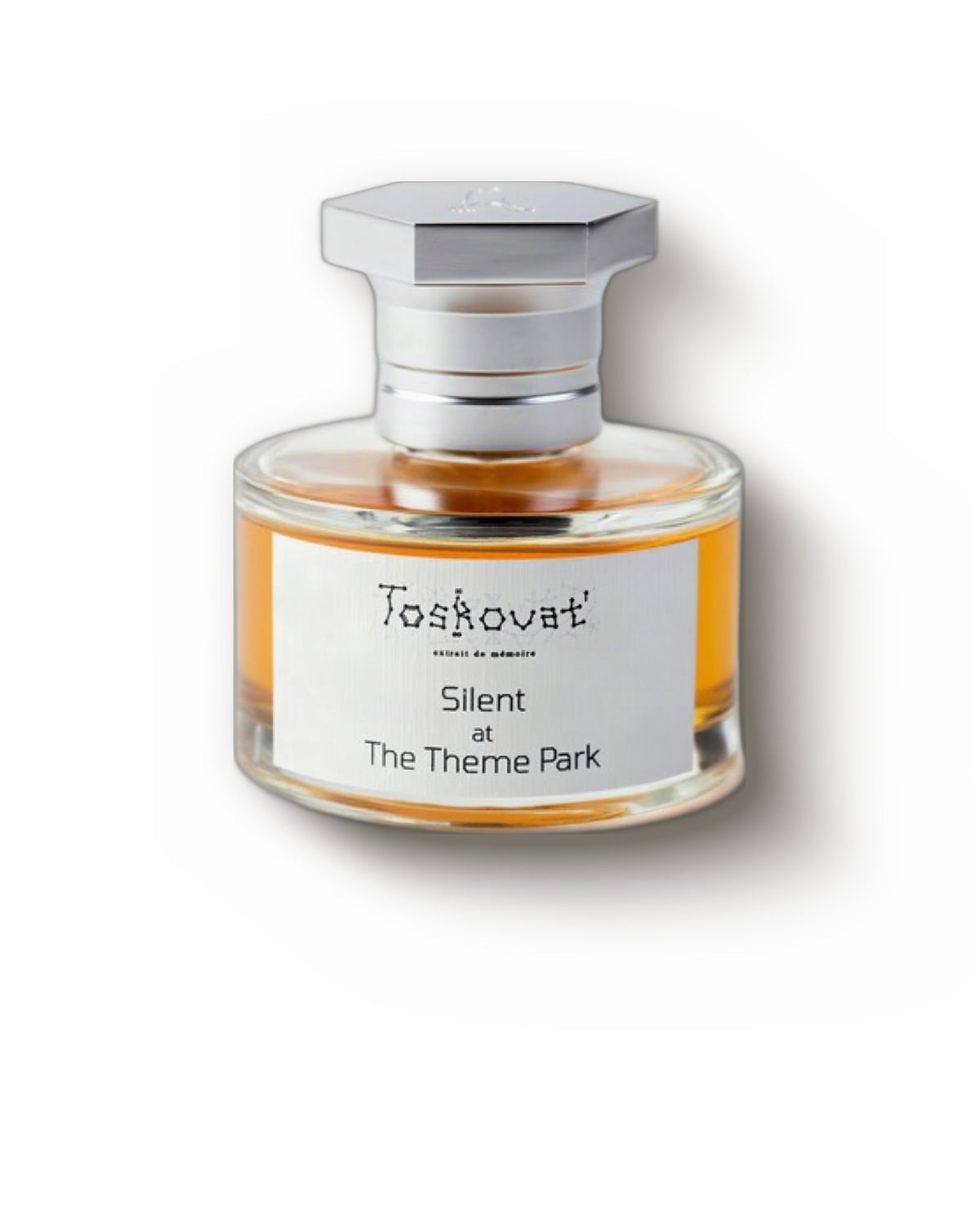 Toskovat Silent at the Theme Park, front view: a round clear bottle of amber juice under a hexagonal brushed-silver cap, its white label printed Toskovat' and Silent at The Theme Park.