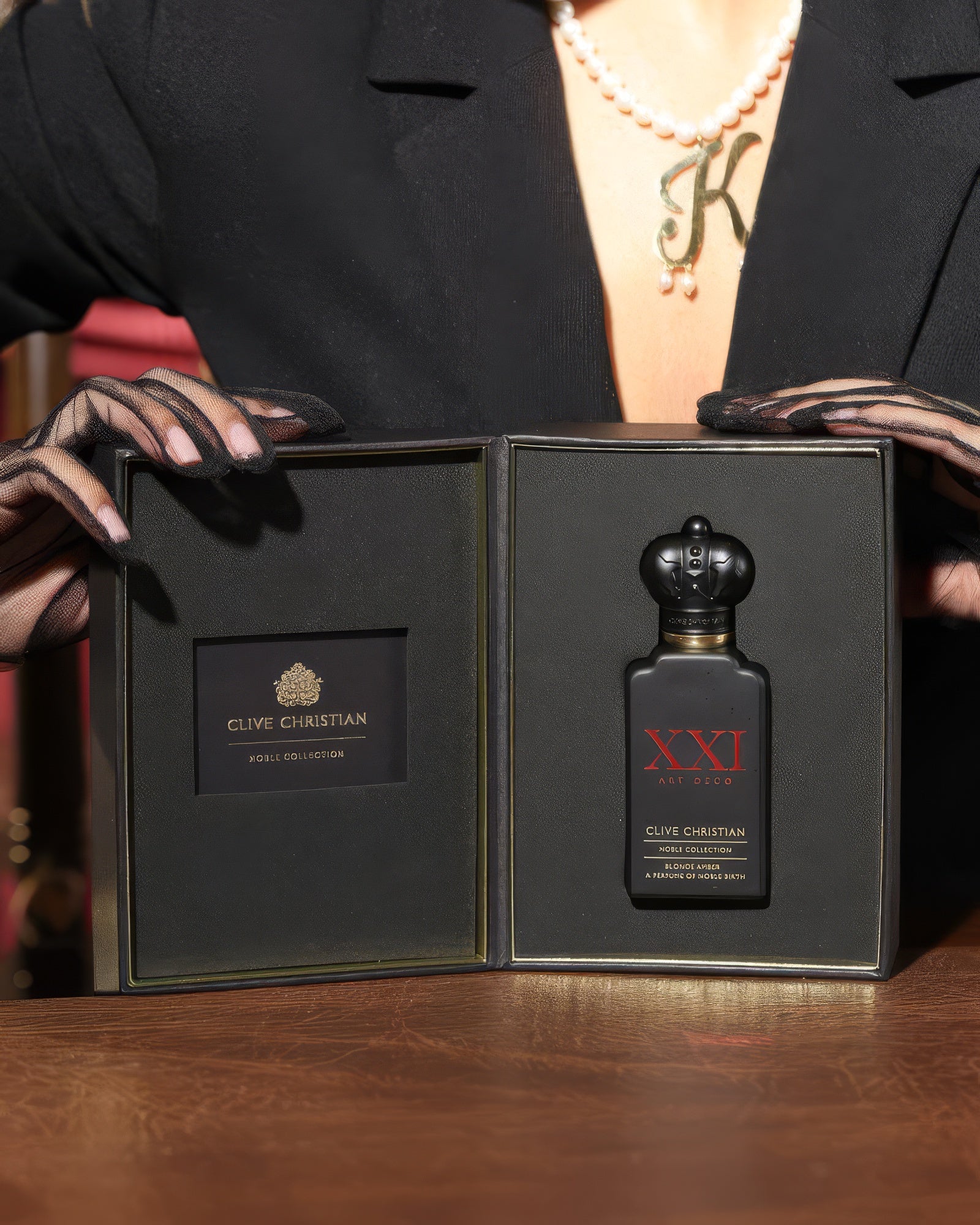 Woman in pearls opening the Clive Christian Blonde Amber gift box, boozy amber niche perfume decant