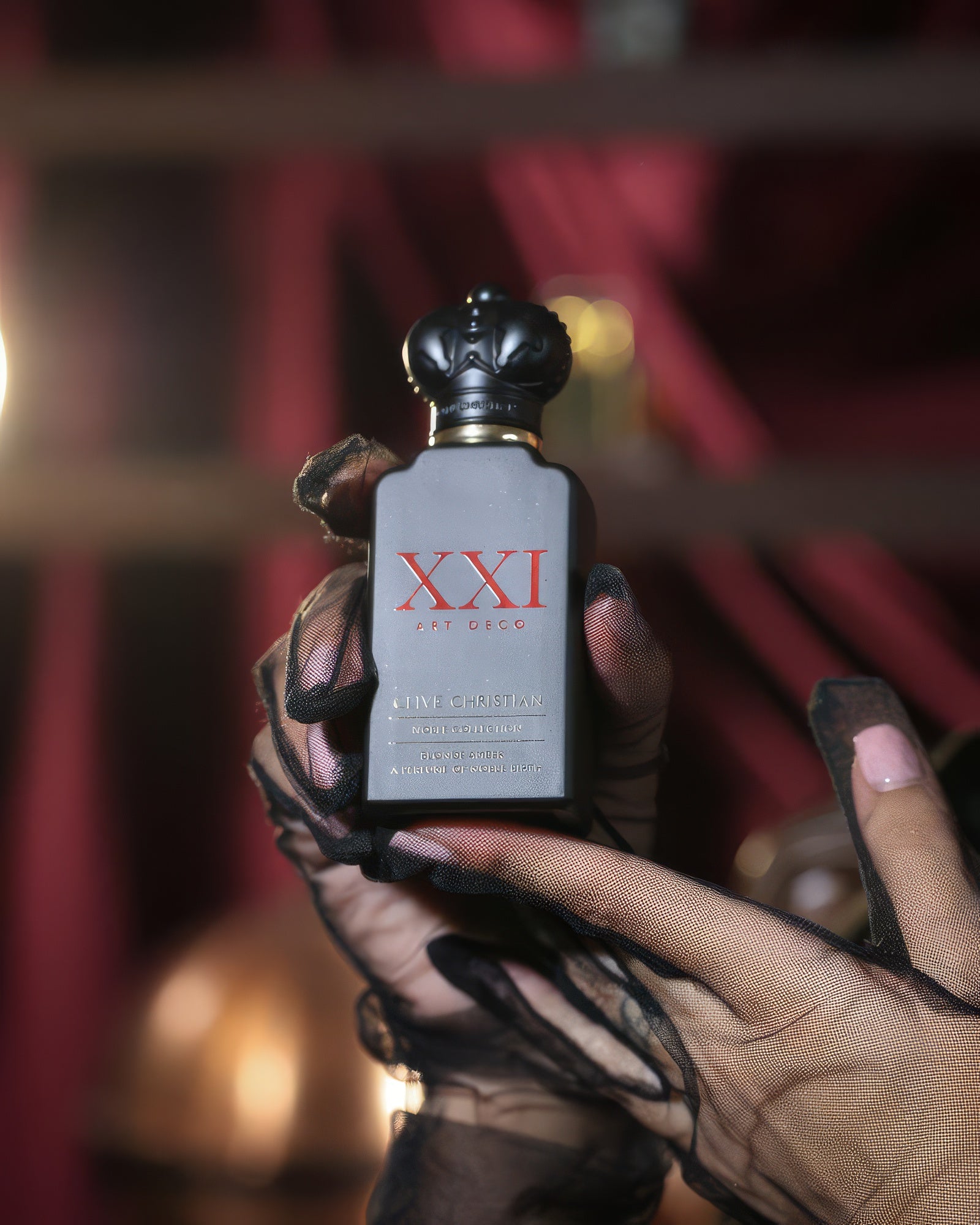 Lace-gloved hands holding Clive Christian Blonde Amber against red velvet, tobacco amber extrait sample