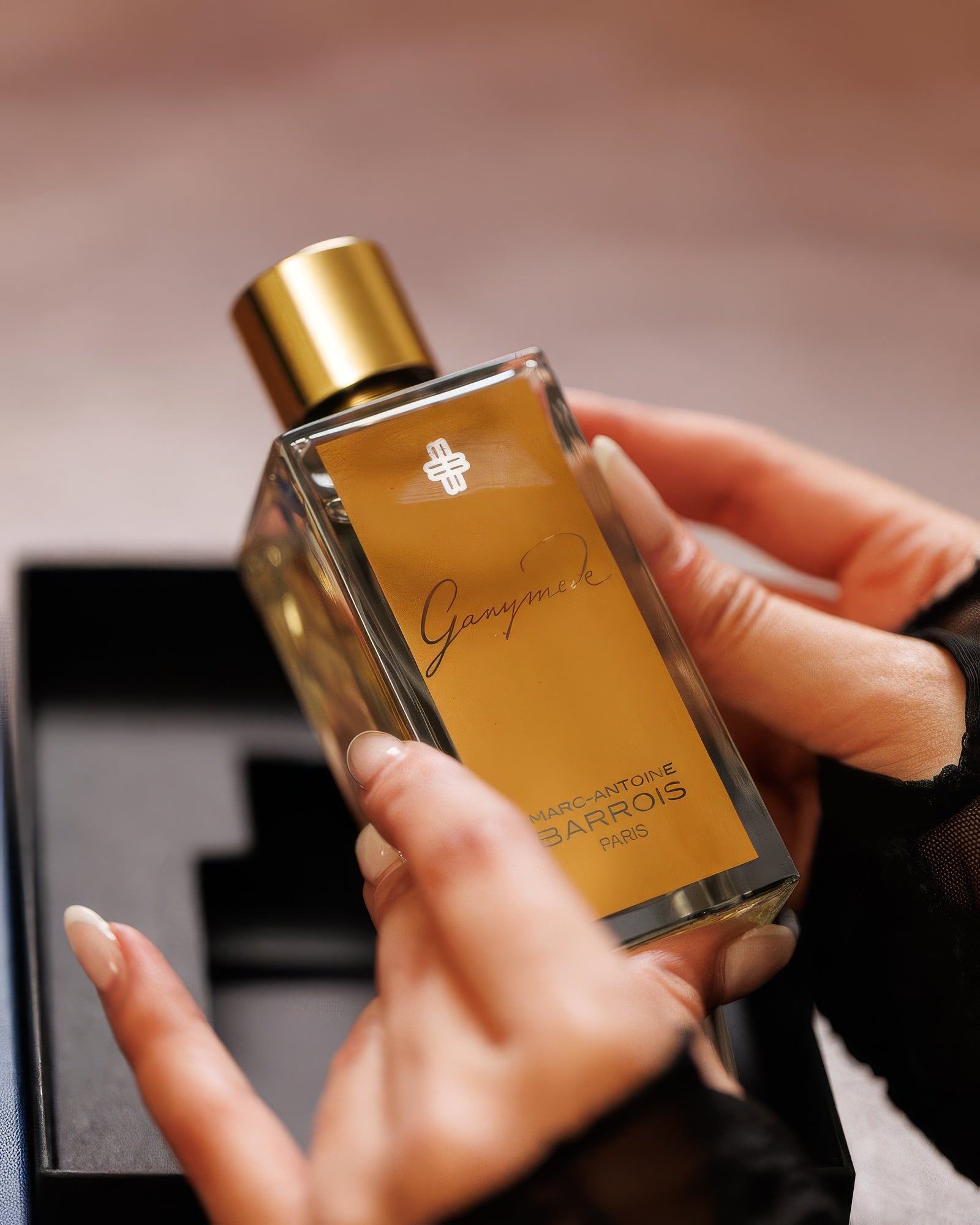 Hands cradling the Marc Antoine Barrois Ganymede bottle above its black box, fresh mineral eau de parfum sample