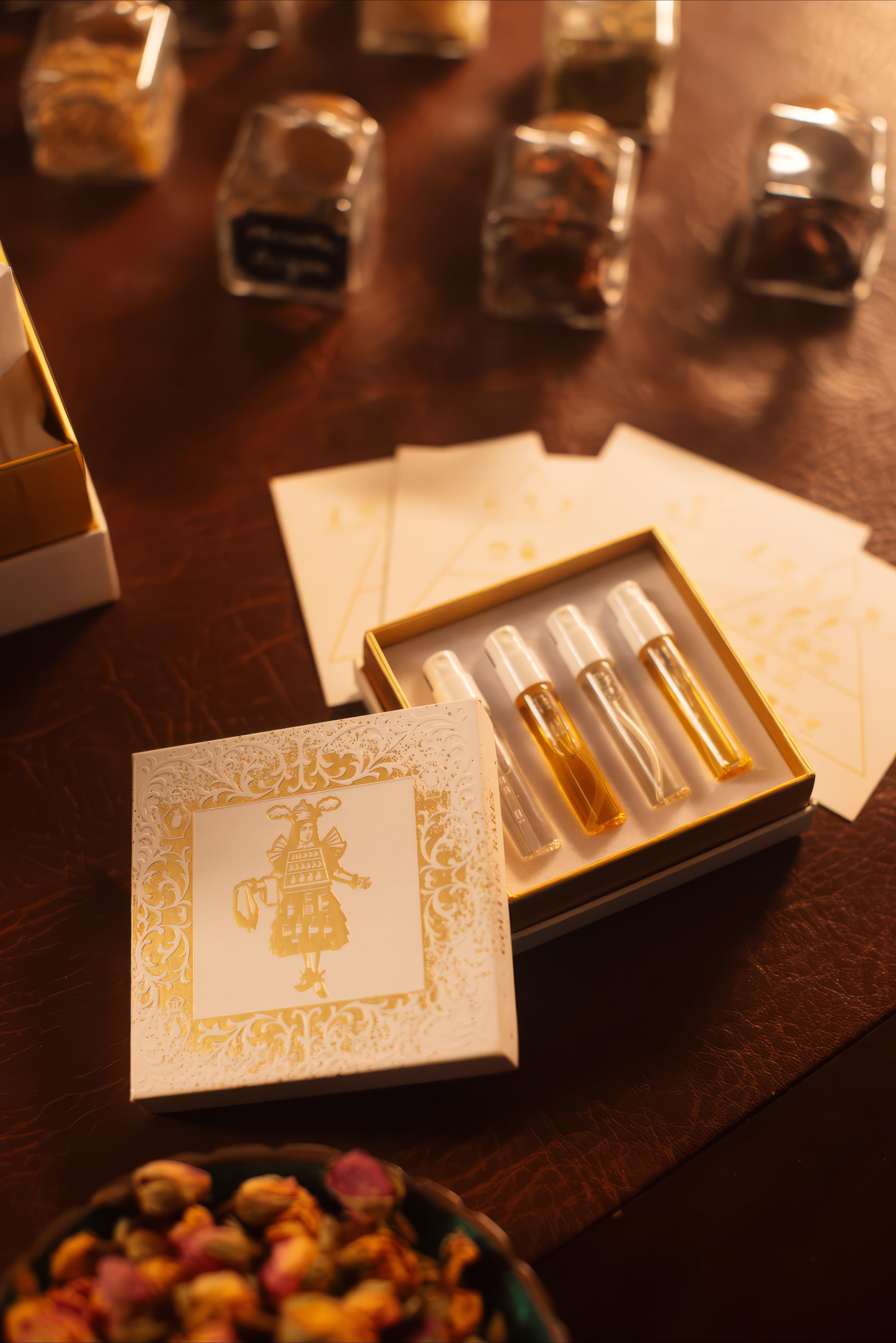 Gouttes Rares discovery set open beside apothecary jars of raw materials, warm-lit niche perfume sampler tray